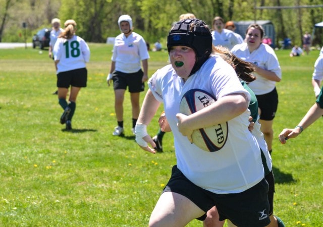 Girl running with a rugby ball.